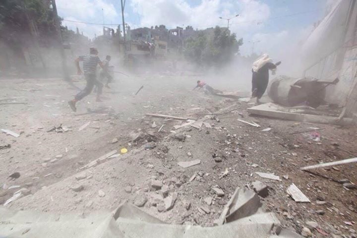 23 juillet 2014 Une femme et quelques passants courent sous un bombardement d'un quartier de Gaza